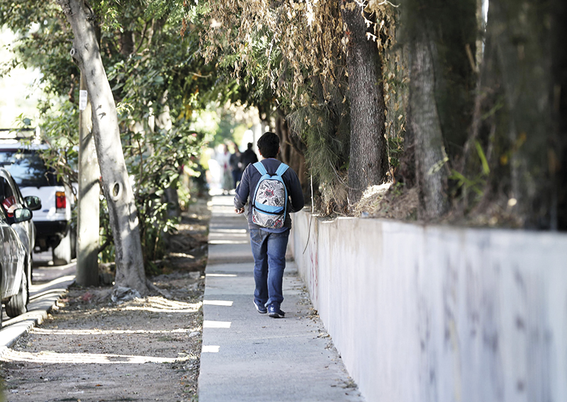 Estudiante caminando por la acera de una calle