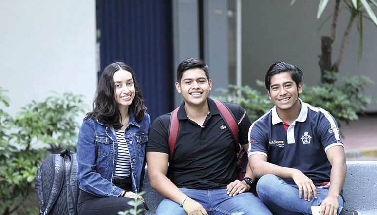 Tres alumnos de la Universidad de Guadalajara sentados y sonriendo para toma de fotografía