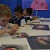 Niños pequeños de primaria, en taller de plastimasa de galaxias, tratando de hacer una de ellas.