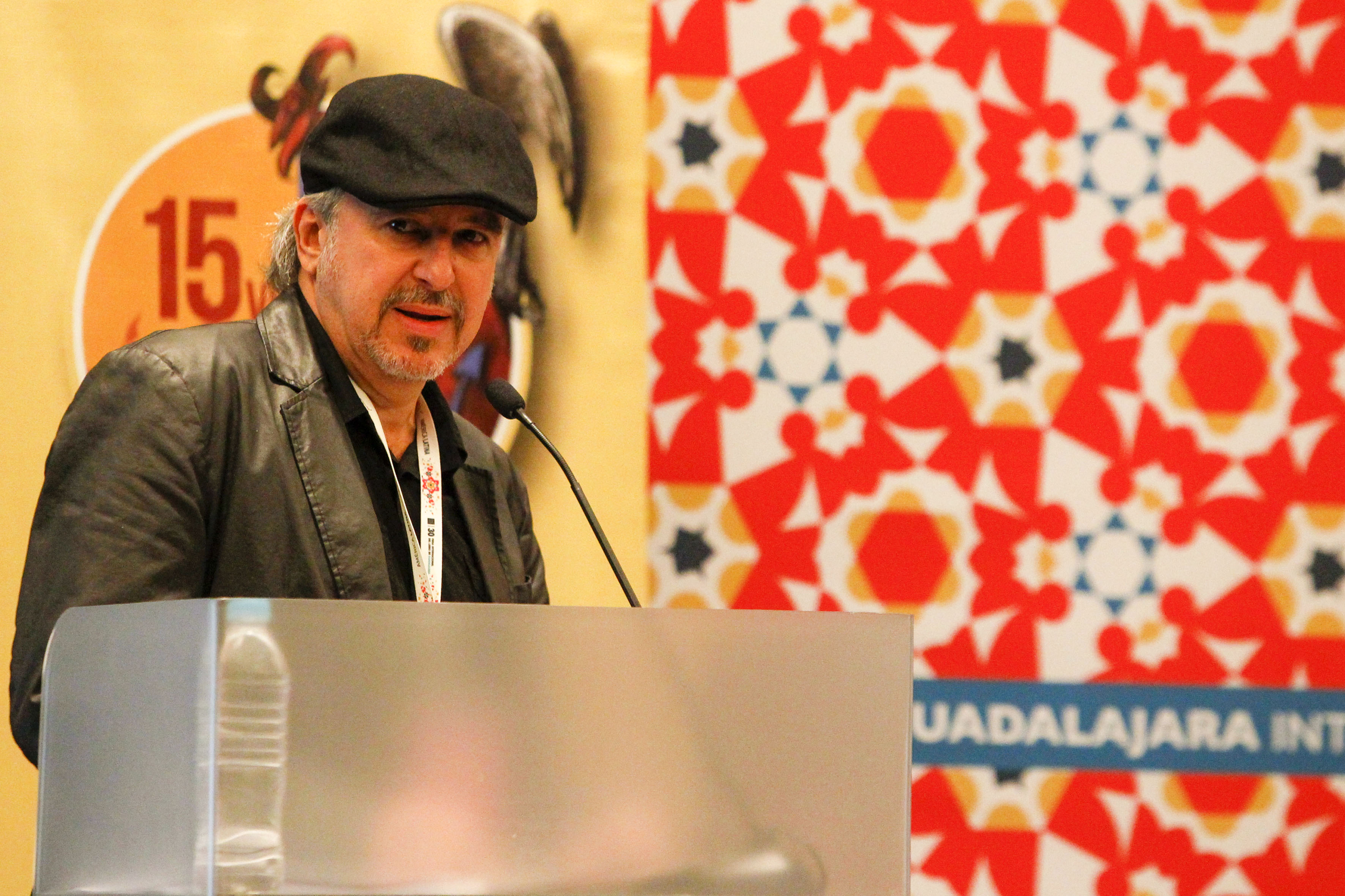 El caricaturista cubano Ángel Boligán, con micrófono en podium del evento, haciendo uso de la palabra.