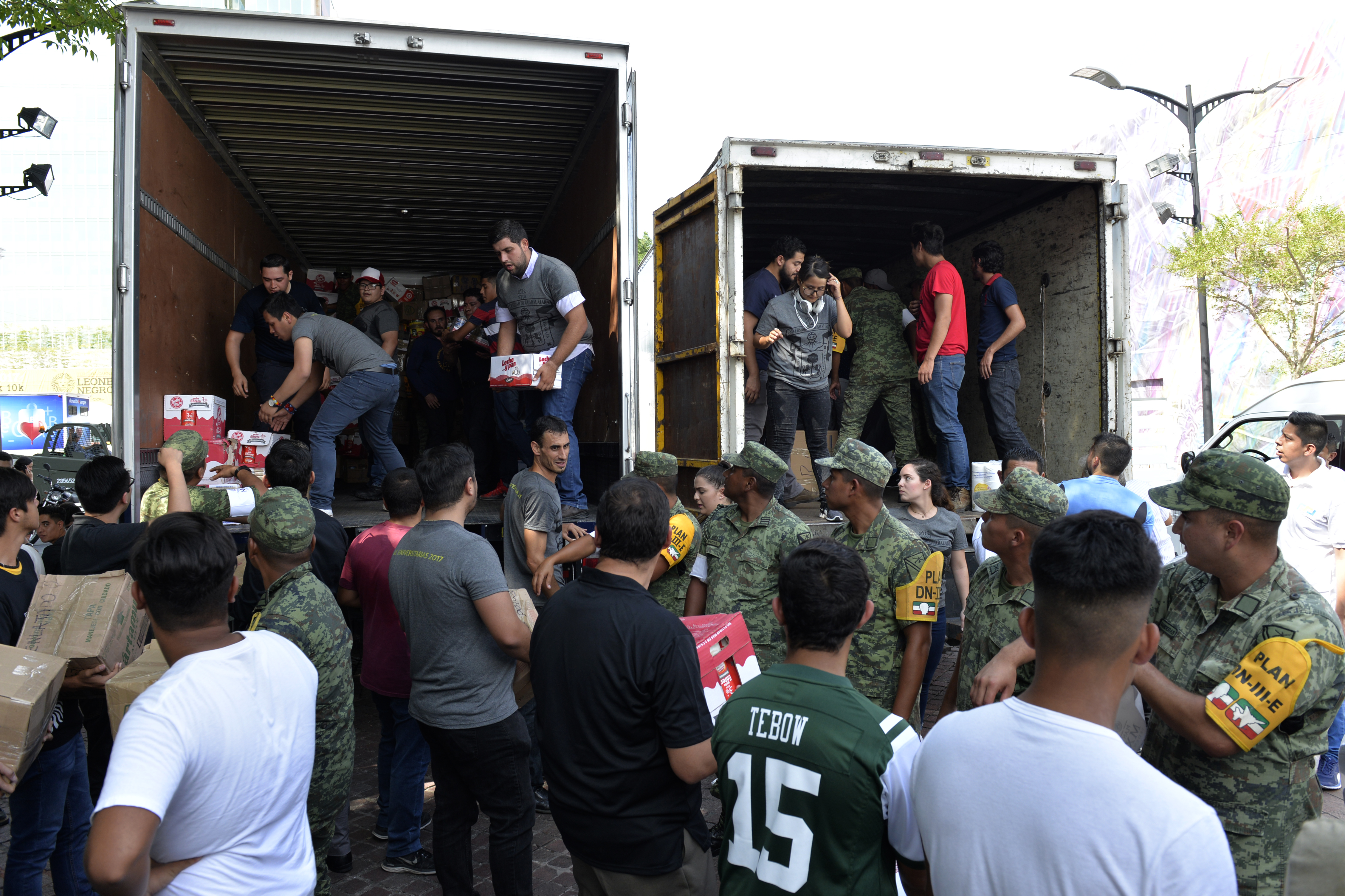 studiantes de la comunidad universitaria y soldados  ayudando a la carga de camiones con viveres 