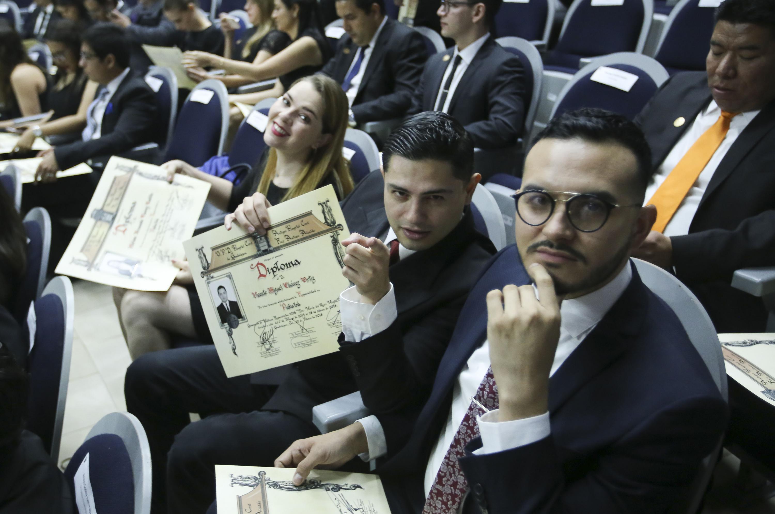 3 egresados (Una mujer y dos hombres) muestran su diploma de acreditación