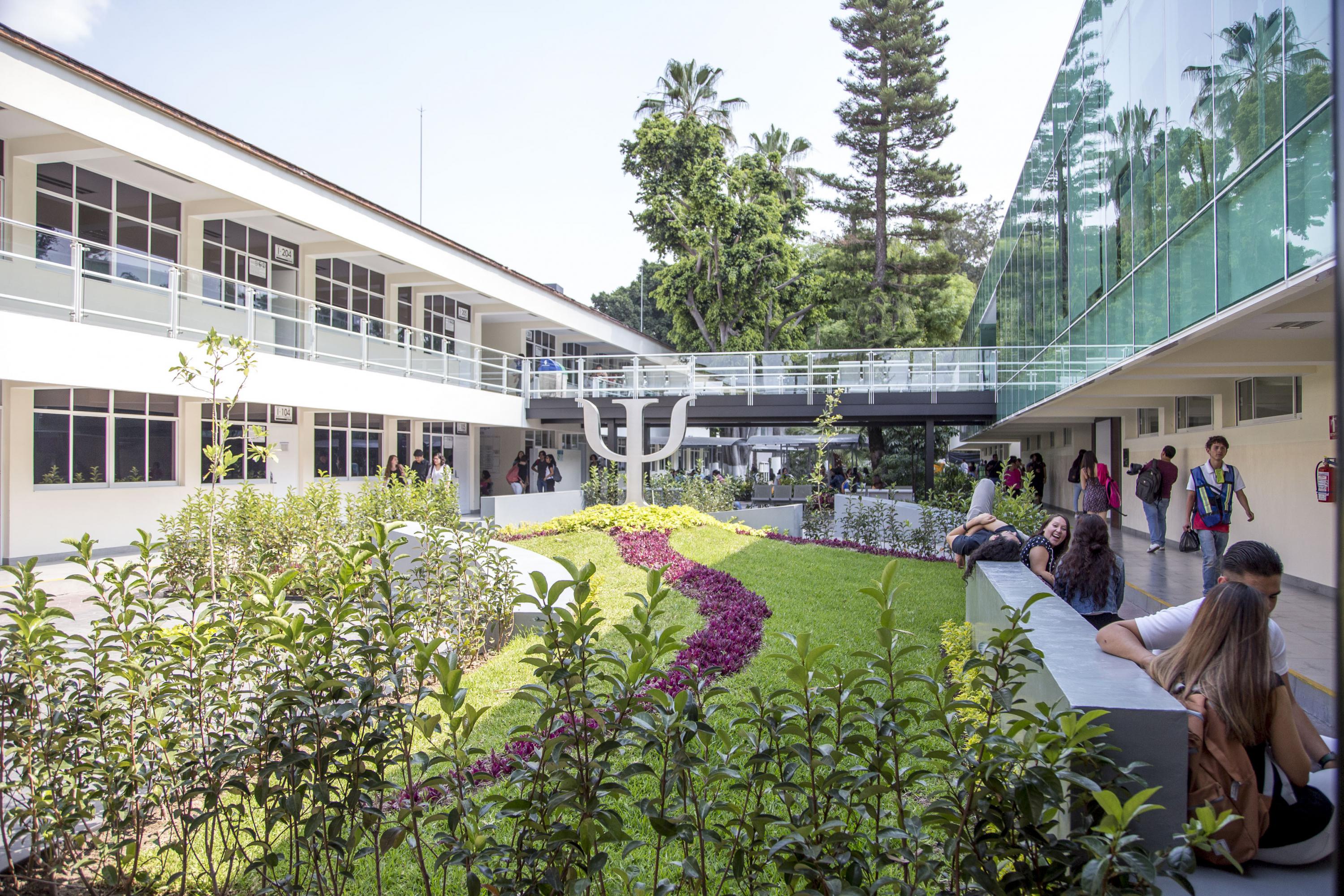 Vista desde el jardín del CAPIB, se ven varios estudiantes sentados en bancas conversando