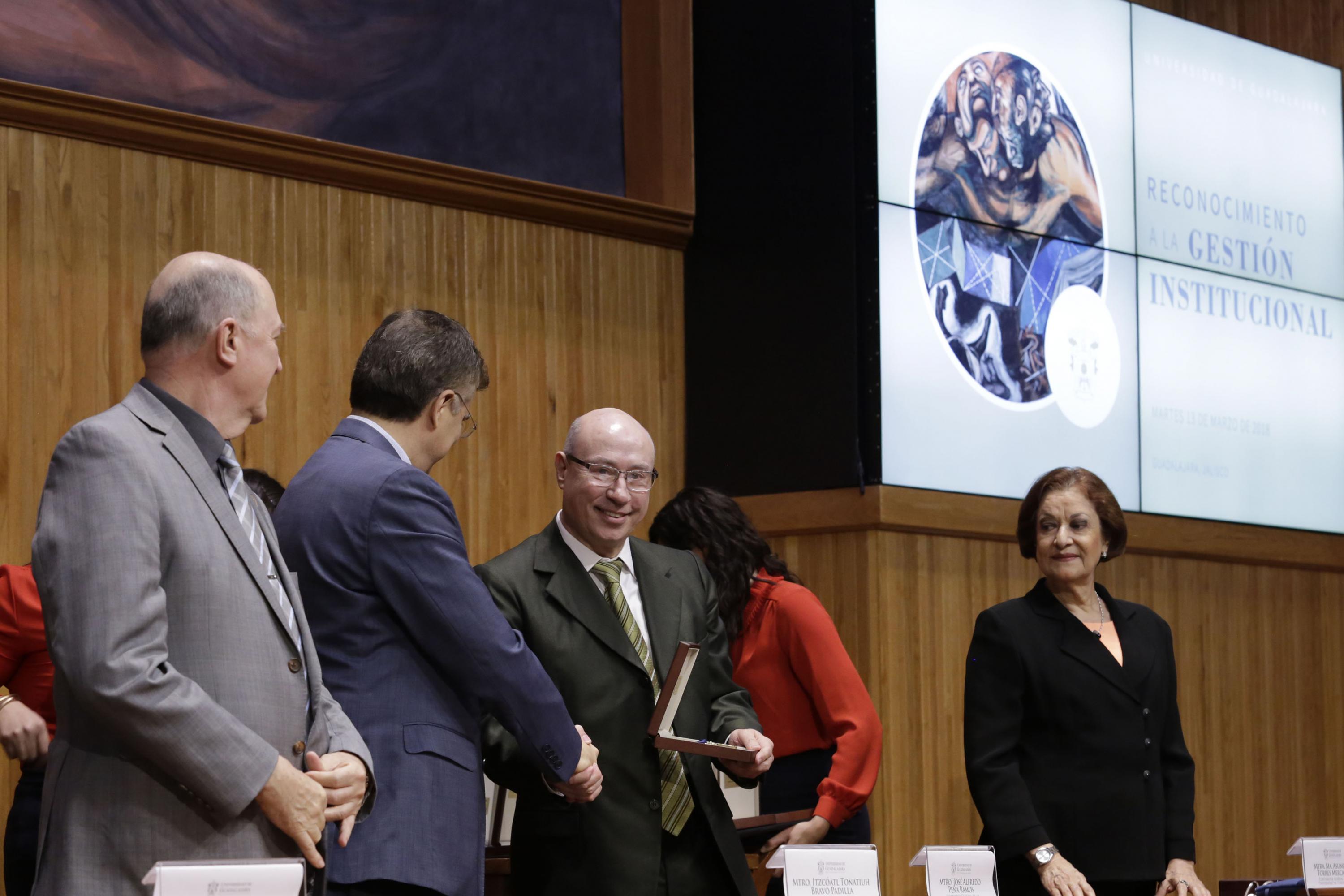 Rector General de la Universidad de Guadalajara (UdeG), maestro Itzcóatl Tonatiuh Bravo, haciendo entrega de reconocimiento al  Secretario General, maestro José Alfredo Peña Ramos