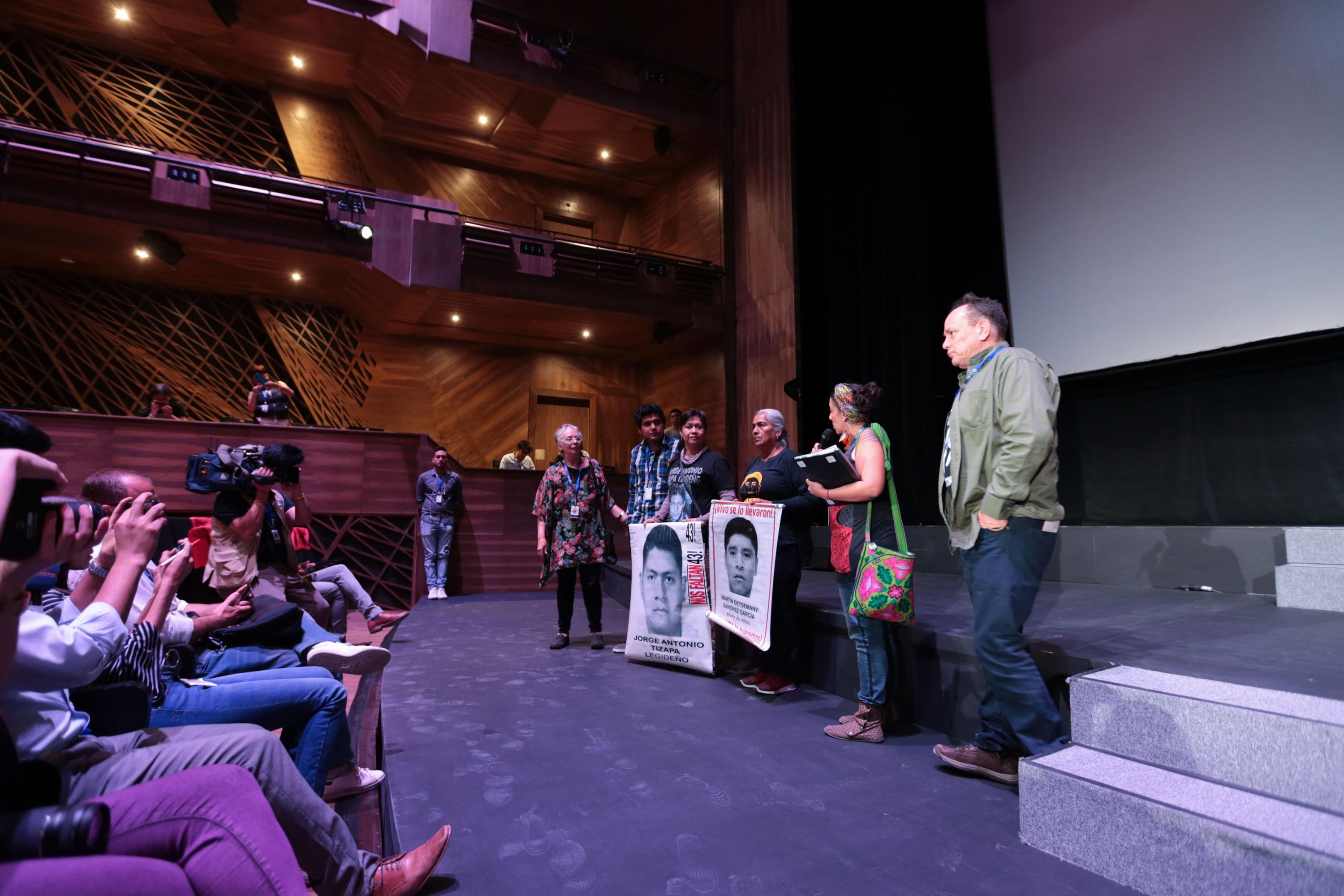 Afectados de los sucesos ocurridos en Ayotzinapa, a un lado del director del filme y la productora. 