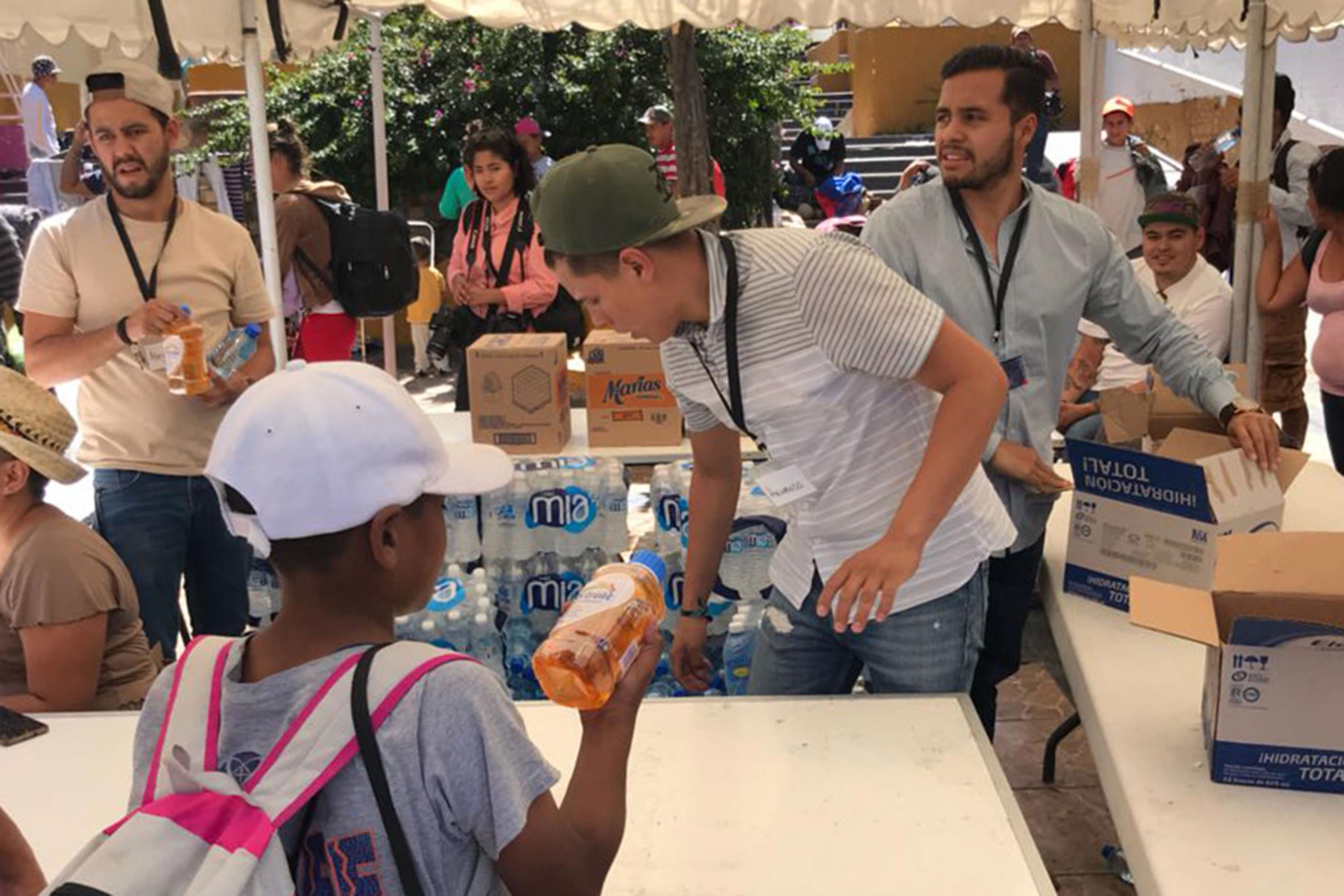 Voluntarios haciendo entrega de botellas de agua y electrolitos a los migrantes
