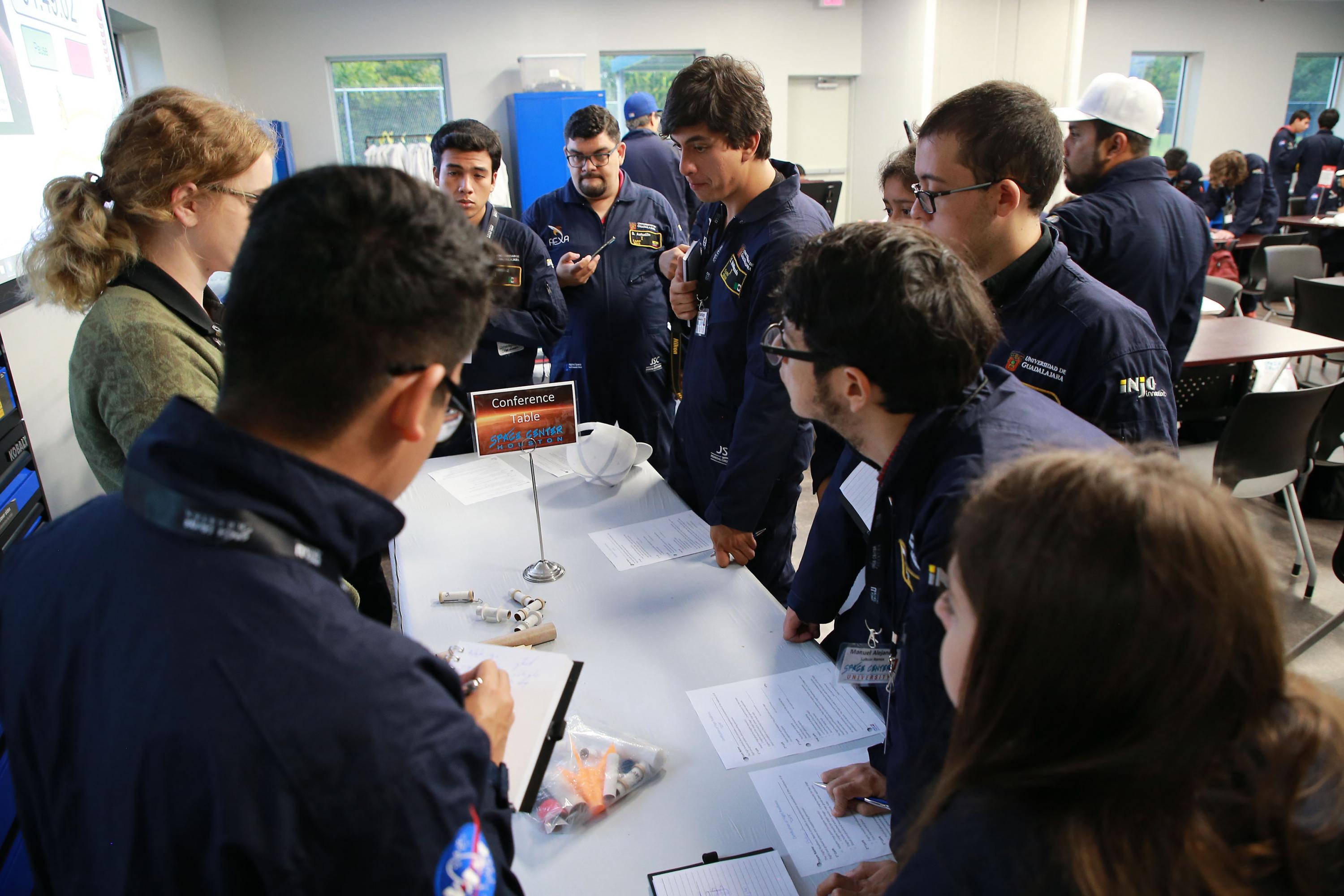 Un grupo de participántes prestan atencion a la explicacion de uno de los expertos de la NASA