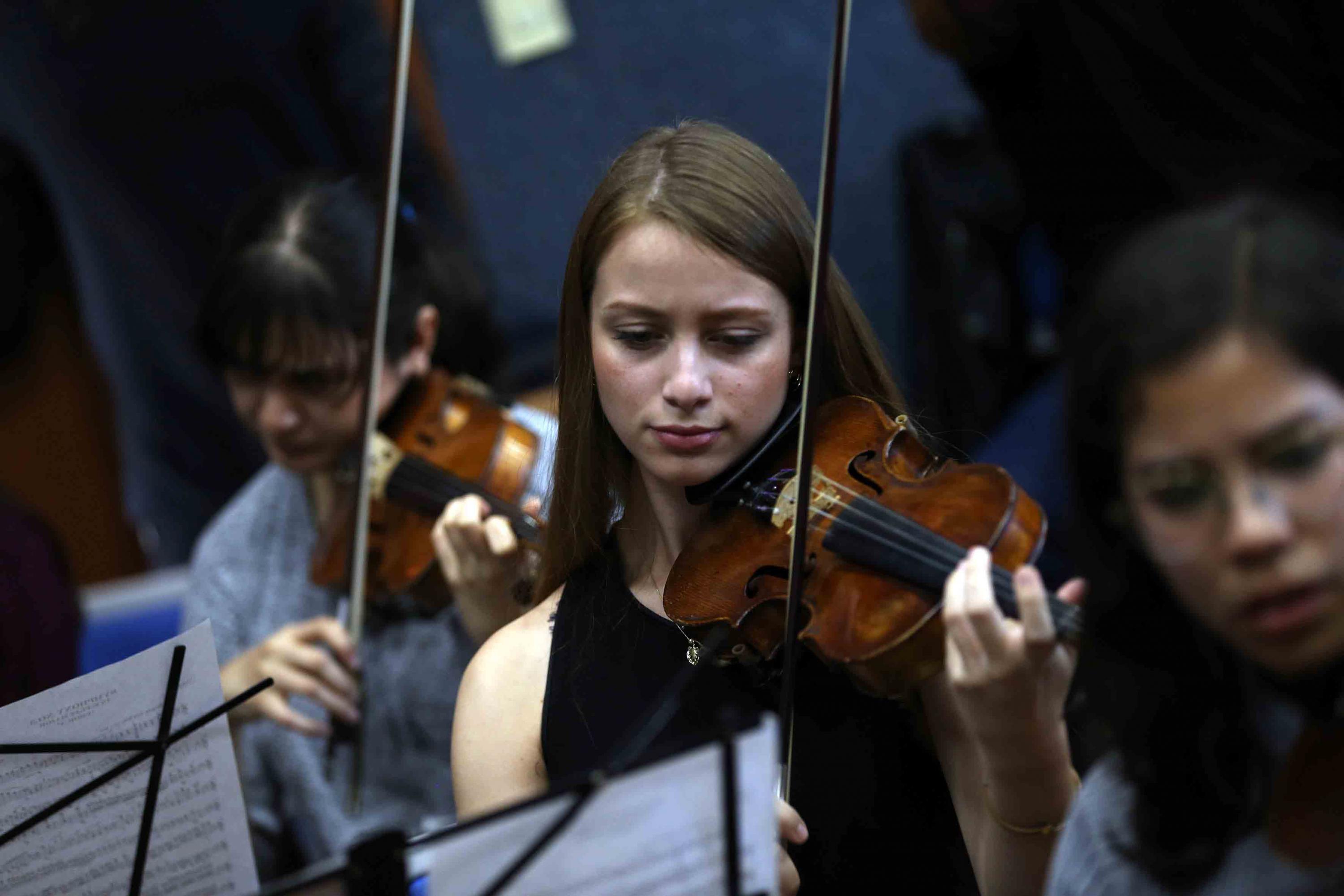 Una joven de la orquesta sinfonica tocando el violin
