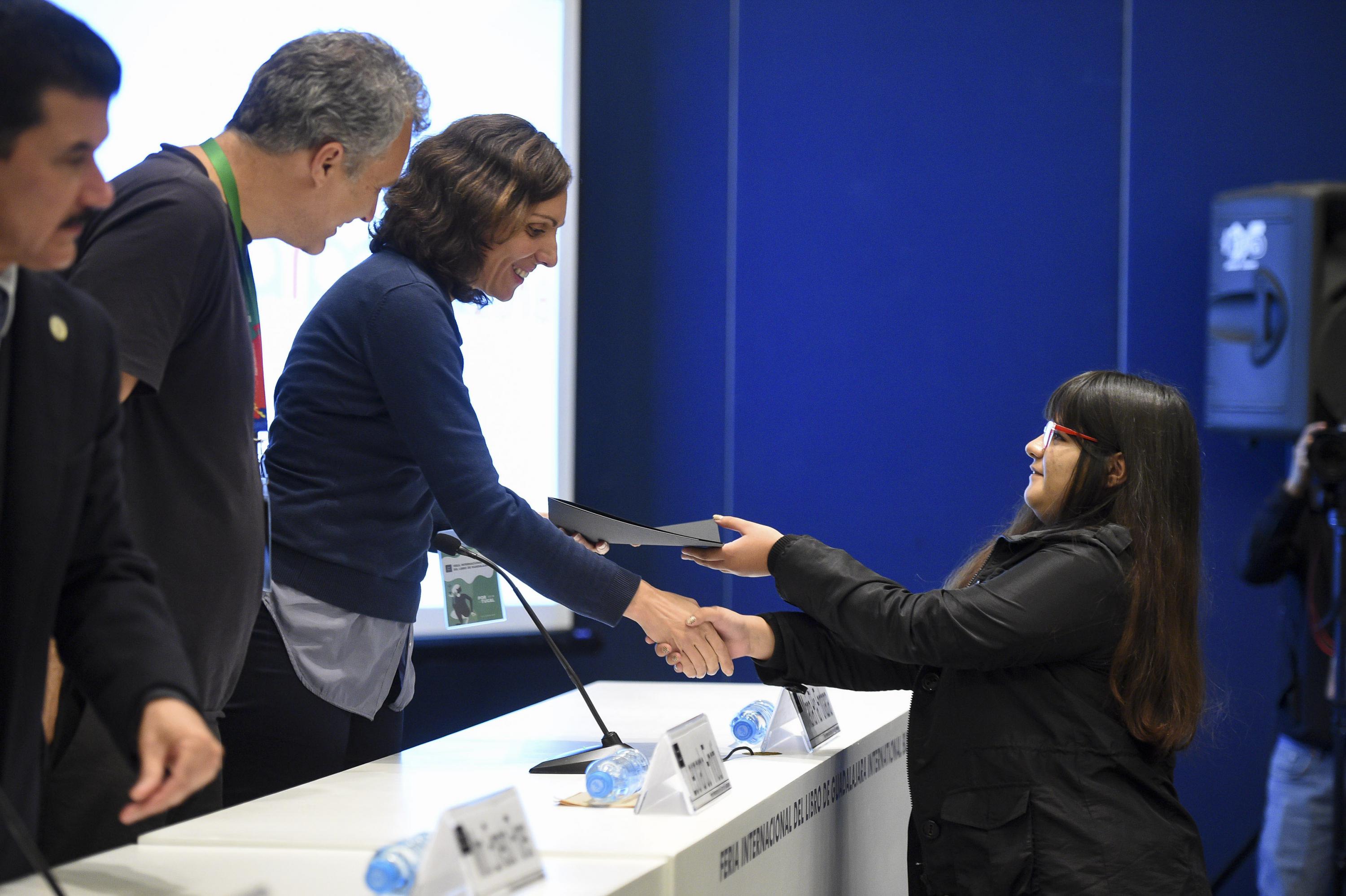 Una joven estudiante recibiendo el premio de parte del jurado.